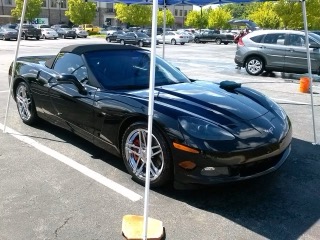 Black Corvette sports car parked in lot with white pole marker