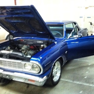 Blue classic convertible car with open hood displayed at auto show