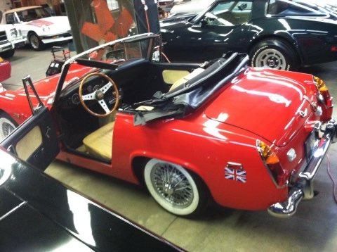 Red vintage convertible sports car with white wall tires displayed at car show