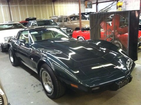 Black Chevrolet Corvette sports car displayed in indoor showroom with other vehicles visible in background